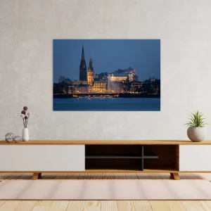 Blick über die Alster auf Rathaus, Nikolaikirche und Elbphilharmonie bei Nacht.